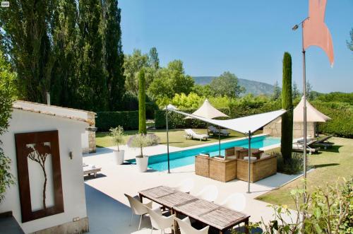 un patio extérieur avec une table et des chaises ainsi qu'une piscine dans l'établissement Les Cerisiers maison bertuli climatisé, Piscine chauffée, lit King size, classé 5 étoiles, à Oppède