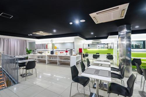 a dining room with white tables and chairs at Swift Inn Aeropolis Airport in Tangerang