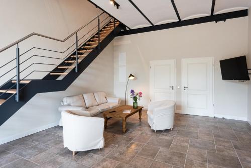 a living room with white furniture and a staircase at Storchenhof Blumenow in Blumenow