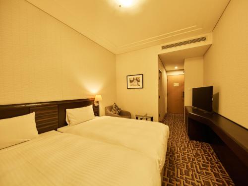 a hotel room with two beds and a flat screen tv at Okura Chiba Hotel in Chiba