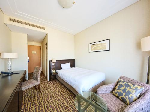 a hotel room with a bed and a desk and chairs at Okura Chiba Hotel in Chiba