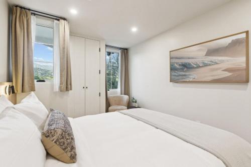 a white bedroom with a bed and a window at Casa Riviera - Boutique Apartments in Downtown Santa Barbara in Santa Barbara