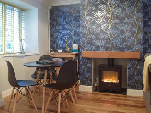a dining room with a table and a fireplace at Castle Street Cottage in Narberth