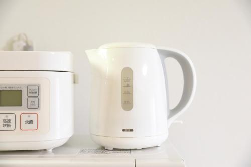 a white appliance sitting next to a microwave at シティラデファンス - 2025年6月室内リニューアル in Sapporo