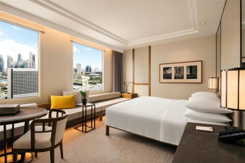 a hotel room with a bed and a desk and a table at Conrad Singapore Marina Bay in Singapore