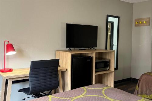 a bedroom with a desk and a television and a chair at Super 8 by Wyndham Evansville East in Evansville