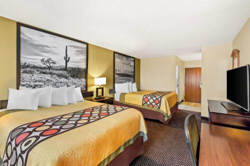 a hotel room with two beds and a flat screen tv at Super 8 by Wyndham Marana/Tucson Area in Tucson