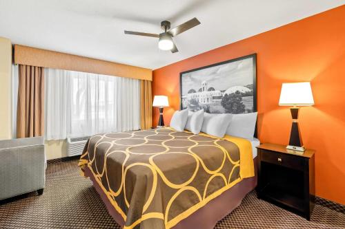 a hotel room with a bed with orange walls at Super 8 by Wyndham Marana/Tucson Area in Tucson