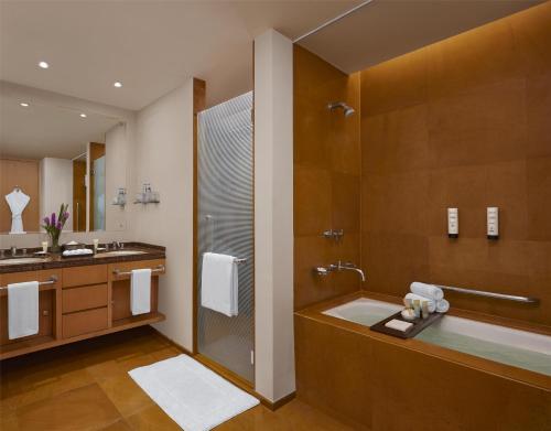 a bathroom with a shower and a sink and a tub at Grand Hyatt Mumbai Hotel and Residences in Mumbai