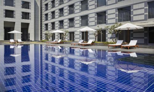 a swimming pool with chairs and umbrellas in front of a building at Grand Hyatt Mumbai Hotel and Residences in Mumbai