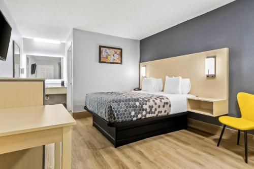 a hotel room with a bed and a yellow chair at Econo Lodge Inn & Suites Cayce I-26 Airport in Cayce