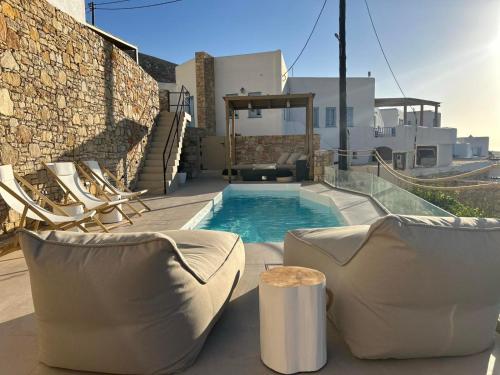 a backyard with a pool and chairs and a house at ANDELIAS Signature Suites in Chora Folegandros