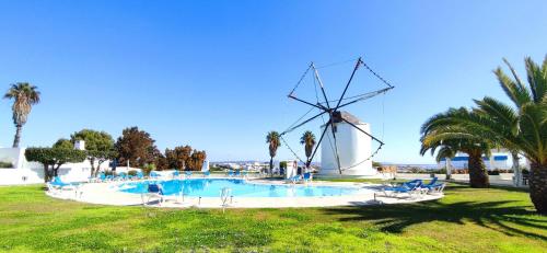 une piscine avec un moulin à vent en arrière-plan dans l'établissement Luxury Townhouse in Top Complex with Town and Ocean View by Be Cherish, à Albufeira