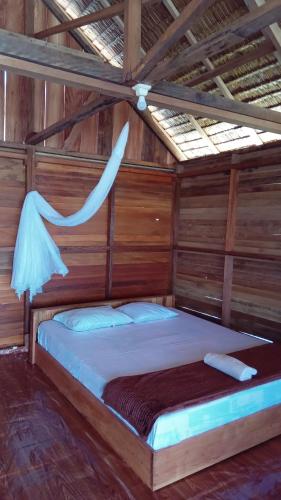 a bed in a room with a wooden wall at Sehati Homestay - Raja Ampat in Besir