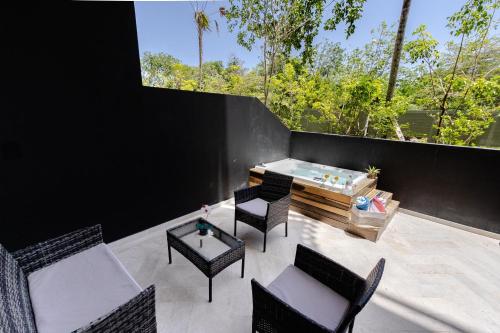 a patio with chairs and a table and a hot tub at Apartment with Private Jacuzzi, Rooftop Pools & Free beach club in Tulum