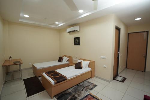 a room with two beds and a table and a door at RIshikulam Wellness Centre in Samālkha