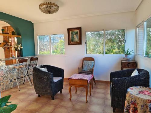 a living room with chairs and a table and windows at Buenas vistas y privacidad, tranquila y fresca villa en el bosque de Valencia con una magnífica piscina de 80m2 in Lliria