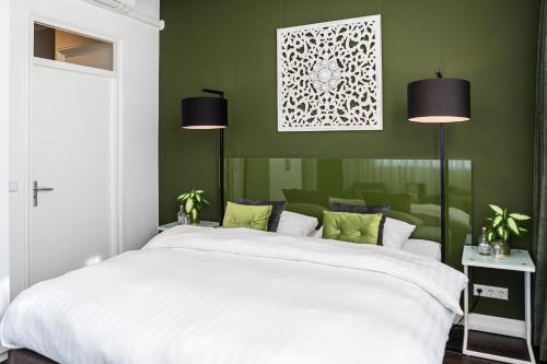 a bedroom with a large white bed with green walls at Pension Montmaertre in Zierikzee