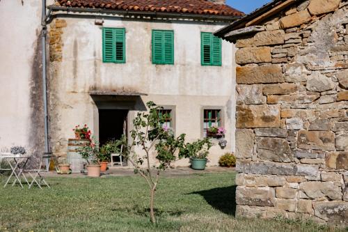a building with green shutters and a tree in front of it at Posestvo Brida - Brkini Hills by the Lakes in Ilirska Bistrica