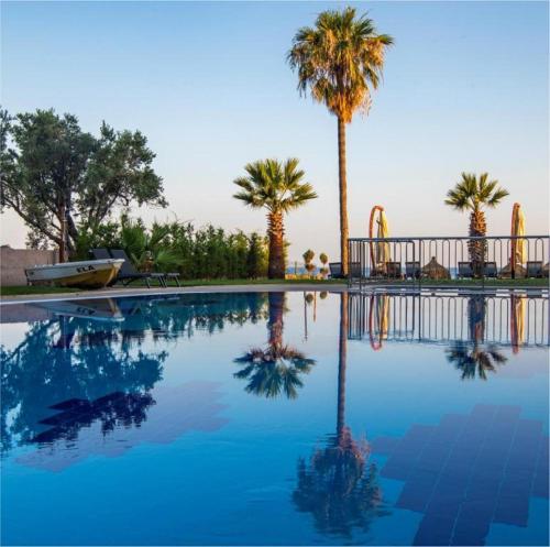 a swimming pool with palm trees in the background at MAIA Luxury Beach Hotel & Spa in Guzelcamlı