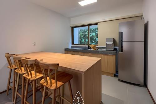 a kitchen with a large wooden table and a refrigerator at Villa Naluri - Seu Refúgio a 50 metros da praia em Japaratinga in Japaratinga