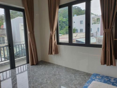 a room with two windows with brown curtains at Happy House Gành Dầu in Phu Quoc