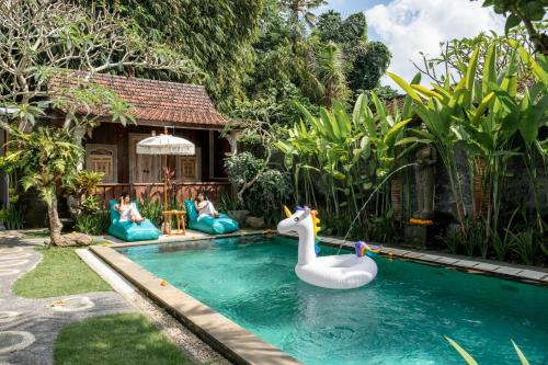 a pool with a swan float in a backyard at Clamonic Villa Ubud - Monthly Rental Available in Sukawati