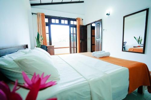a bedroom with a large white bed and a mirror at Highclere Villa in Kamburugamuwa