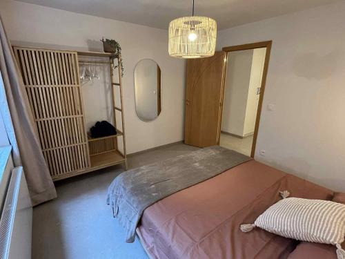 a bedroom with a bed and a mirror and a chandelier at Modern appartement in Oostende op Toplocatie! in Ostend