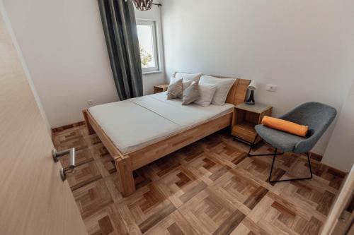 a small bedroom with a bed and a chair at Elia apartments in Ražanj
