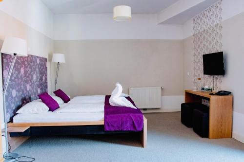 a bedroom with a white bed with purple pillows at Hotel Zur Schonenburg in Schonberg am Kamp
