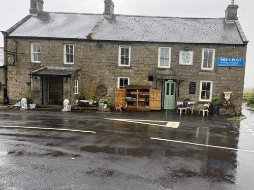 an old brick building in the rain with a parking lot at Bird In Bush Elsdon in Elsdon
