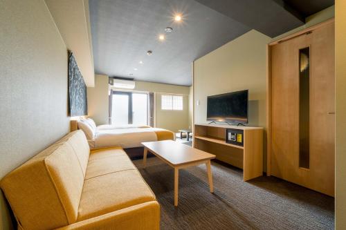 een hotelkamer met een bank en een tv bij RESI STAY ANDON in Kyoto