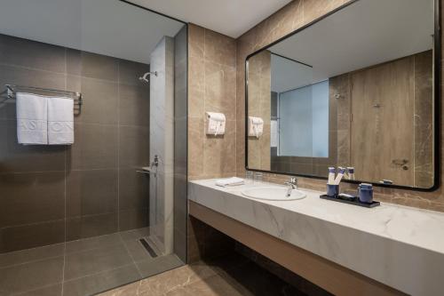 Un baño con lavabo, ducha y espejo. en Aston Inn Lumajang - East Java, en Lumajang