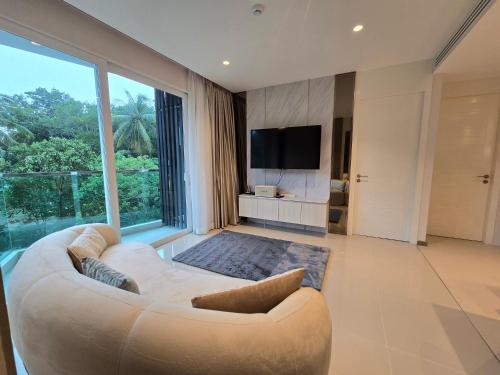 a living room with a white couch and a large window at Luxury Condo The City Phuket in Heart of Phuket in Kathu