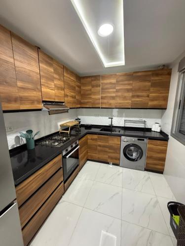 a kitchen with wooden cabinets and a stove top oven at Appart Résidence Sabrin in Fnidek