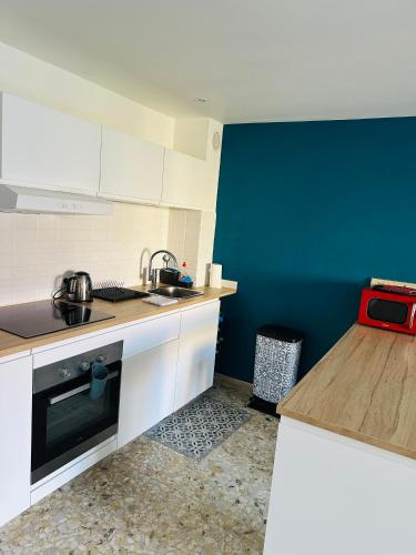 une cuisine avec des armoires blanches et un mur bleu dans l'établissement T1 Ensoleillé avec Balcon Mourillon Plages, Toulon, à Toulon