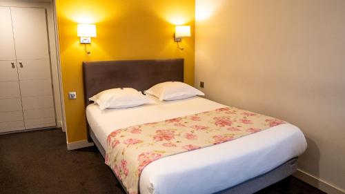 a bedroom with a large bed with two pillows at Grand Hôtel d'Orléans in Toulouse
