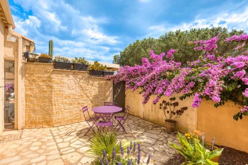 a patio with a purple table and purple flowers at La Palmeraie - Chambre Musique in Portiragnes