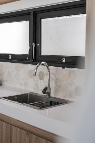a kitchen counter with a sink and two windows at Charming 1BR Villa with Pool and Wooden Interior in Cemagi