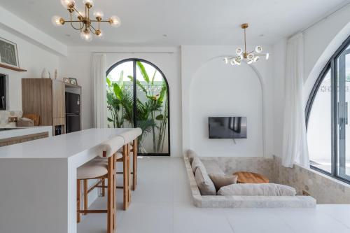 a kitchen and living room with white walls and a large window at Charming 1BR Villa with Pool and Wooden Interior in Cemagi