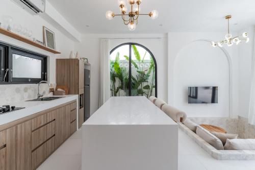 a kitchen with a large white table and a window at Charming 1BR Villa with Pool and Wooden Interior in Cemagi