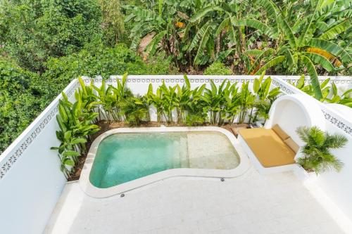 an outdoor swimming pool with plants on a building at Charming 1BR Villa with Pool and Wooden Interior in Cemagi