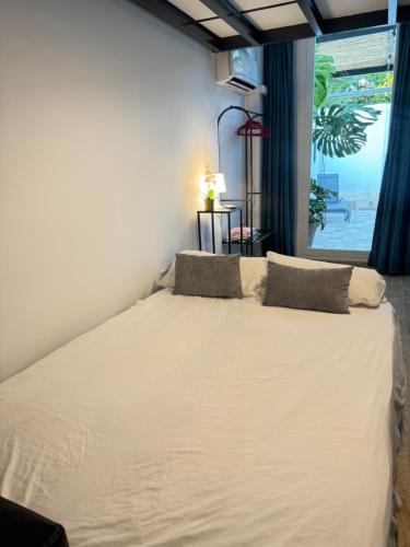 a bedroom with a white bed with a large window at Brisas a un paso del centro in Valencina de la Concepción