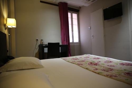 a bedroom with a bed with a flowered blanket on it at Grand Hôtel d'Orléans in Toulouse