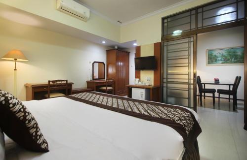 a hotel room with a bed and a desk and a table at Hotel Grand Trisula Indramayu in Indramayu