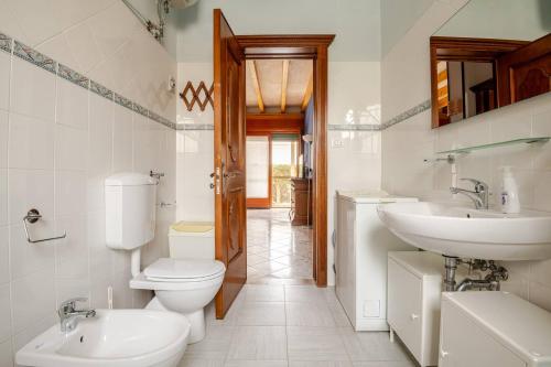 a white bathroom with a toilet and a sink at Redlands House - casa vacanze in Uggiano la Chiesa