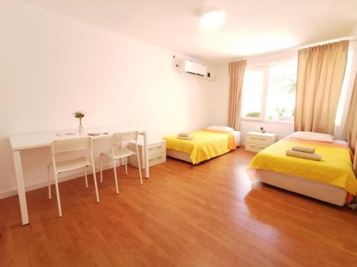 a bedroom with two beds and a desk and a table at Studio Garden City Center Pomorie in Pomorie