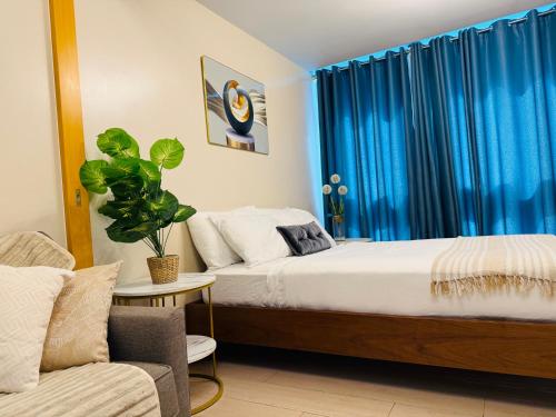 a bedroom with a bed with blue curtains and a couch at Modern Suite In Bonifacio Global City in Manila