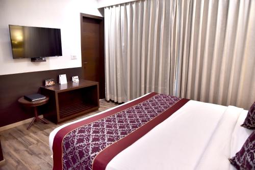 a hotel room with a bed and a flat screen tv at Clarks Inn Suites Gwalior in Gwalior